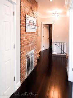 an empty hallway with brick wall and wooden flooring is seen in this image from the doorway