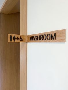 a wooden sign that says bathroom on the side of a wall next to a toilet