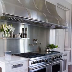 a stainless steel stove top oven in a kitchen with white cabinets and wood flooring