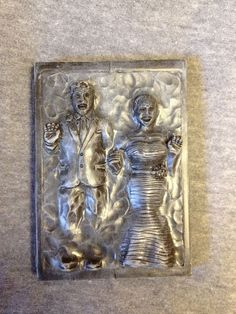 a metal plaque with two people in the middle and one woman standing next to her