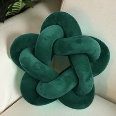 a green knot pillow sitting on top of a white couch