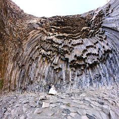 the bride and groom are standing in front of an unusual rock formation that looks like it has been carved out of wood