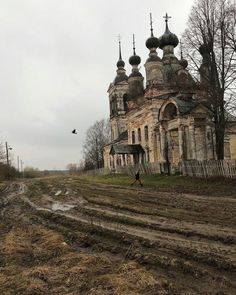 an old abandoned church in the middle of a field with mud and grass on the ground