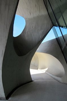 the inside of an architectural building with curved concrete walls and large circular holes in the ceiling