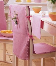 a chair with a pink cover on it sitting in front of a table and bowl of fruit