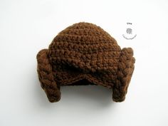 a brown crocheted hat with ears is shown on a white surface and has a small button in the middle