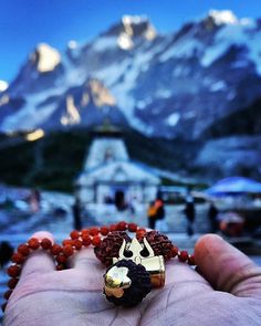 a hand holding a beaded bracelet with a mountain in the backgroung