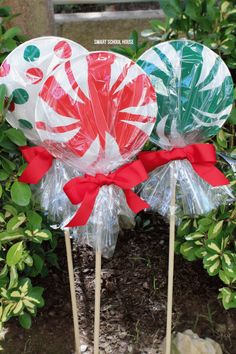 three lollipops wrapped in plastic wrap sitting on top of each other next to some plants