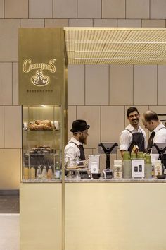 three men standing behind a counter in a restaurant