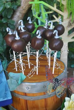 cake pops with chocolate frosting and butterflies on them sitting in a barrel next to flowers