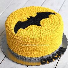 a yellow cake with black icing and a batman symbol on it's side