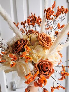 a vase filled with flowers and feathers on top of a table