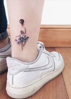 a woman's foot with a tattoo on the ankle that has a ballerina holding a balloon