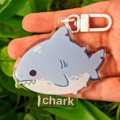 a hand holding a keychain with a shark on it's side and the word id attached to it