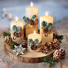 candles with pine cones and snowflakes are arranged on a wooden tray for display