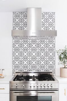 a stove top oven sitting inside of a kitchen next to a wall with geometric tiles on it