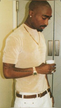 a man holding a cup in his right hand and wearing a chain around his neck