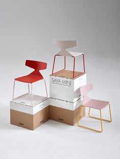 three different colored chairs sitting next to each other on top of cardboard boxes with the same design