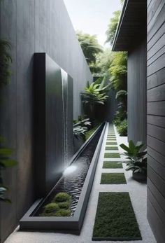 an outdoor water feature in the middle of a walkway with grass and plants on either side