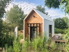 a small building with a wooden deck in the middle of some grass and trees around it