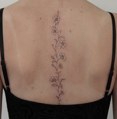 the back of a woman's shoulder with small flowers on her left and right side