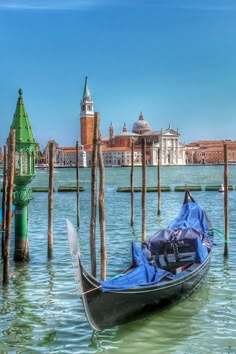 a gondola is tied to poles in the water near a building with a clock tower