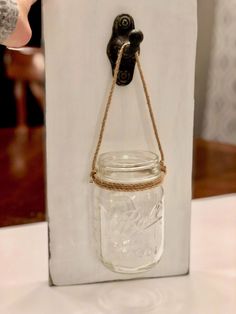 a mason jar hanging on the wall with a rope attached to it and a hook