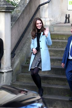 the young woman is walking down the steps waving to someone in her coat and tie