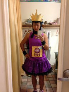 a woman wearing a purple dress and crown taking a selfie in the mirror with her cell phone