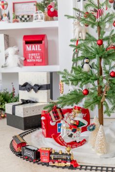 a small christmas tree sitting on top of a table next to a toy train set