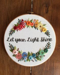 a cross - stitch hoop with the words let your light shine on it, surrounded by flowers