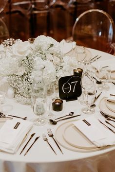 the table is set with white flowers and silverware for an elegant wedding reception or special event