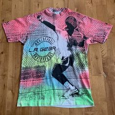 This piece is a vintage L.A. Gear t-shirt from the 1990s. This neon all over print t-shirt has the same graphic on either side of a tennis player and the brand's logo. The shirt itself is made in the USA from 100% cotton with a single stitch construction. It is in good vintage condition with no major flaws. Please also assess the photos and measurements carefully using your own personal judgement. Tag Size: Large, runs slightly smallerPit to Pit: 21"Length: 30"Please see our FAQ's for more info Cheap 90s Style Sports T-shirt, Tennis Tshirts, Tennis Player, Tennis Players, All Over Print, Print T Shirt, Made In Usa, Tennis, Print Design