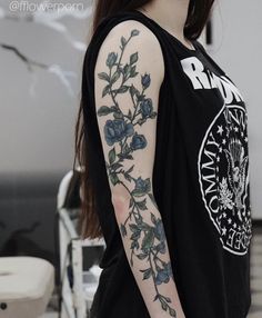 a woman with tattoos on her arm wearing a black tank top