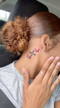 a woman with a cross tattoo on her neck in the back seat of a car