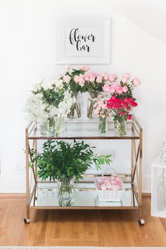 flowers are sitting on top of a shelf in a room with white walls and wooden floors