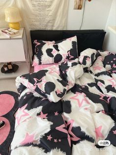 a bed with pink and black stars on the comforter is next to a night stand