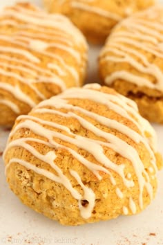 four scones with icing sitting on a white surface