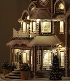 a lit up gingerbread house with snow on the ground