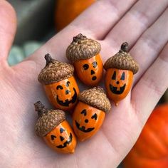 small pumpkins with acorn hats on their heads are held in a person's hand