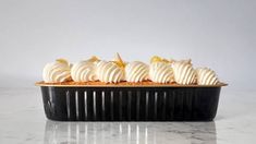 a black dish filled with whipped cream on top of a marble countertop next to a white wall