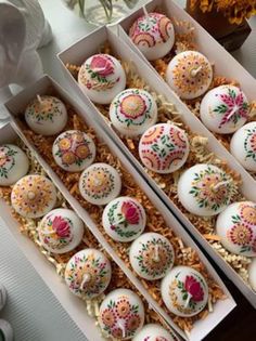 two boxes filled with decorated eggs on top of a table