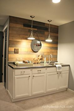 a kitchen with white cabinets and lights hanging from the ceiling