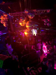 a group of people standing around in a room with disco balls hanging from the ceiling