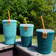 three crocheted cups sitting on top of a wooden table