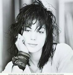 a black and white photo of a woman with her hand on her head, looking at the camera