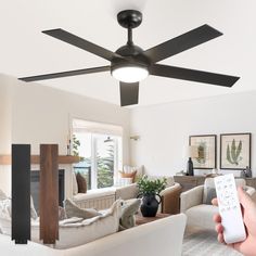 a person holding a remote control in front of a ceiling fan