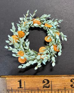 an orange wreath sitting on top of a ruler next to a piece of tape measure