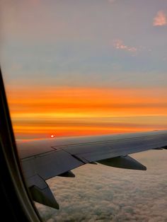 an airplane wing with the sun setting in the distance