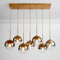 a bunch of shiny glass balls hanging from a ceiling fixture in a room with white walls